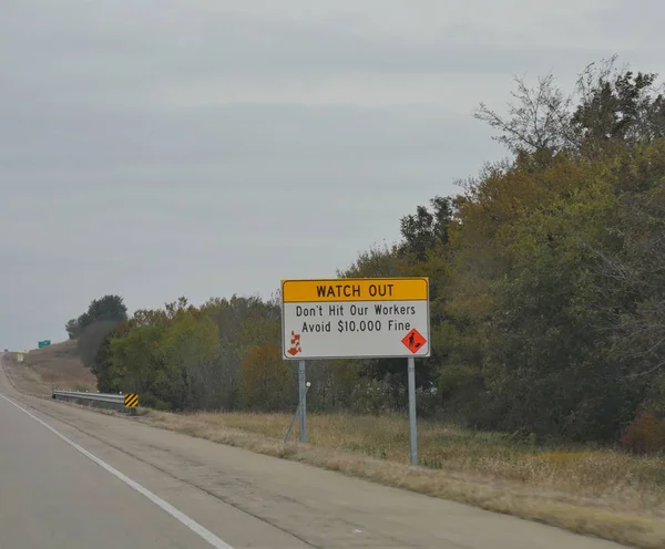 Sign on a roadside to watch out and avoid hitting workers near a road construction site.