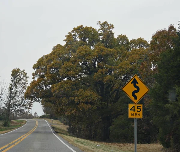 Roadside sign and speed limit warning with the colors of autumn in the trees