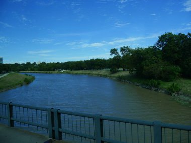 Yol kenarındaki çelik parmaklıklı nehir kenarı manzarası.