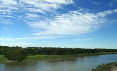 Gökyüzünde muhteşem bulutlar olan nehir kenarı manzarası
