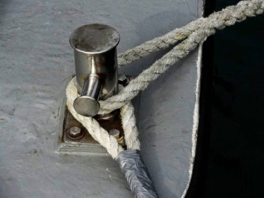 Strong strands of white nautical ropes tied to the dock