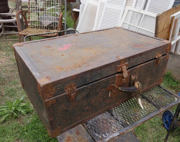 Old rusty metal box and several other junk items at a garage sale