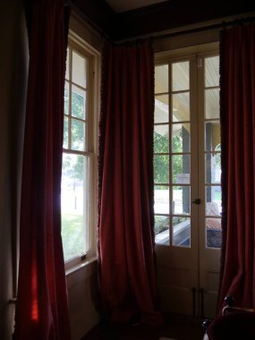 Eski bir evin içinden kırmızı perdeli Fransız pencereleri.