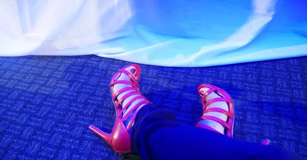 Feet wearing red stilettos in blue carpet