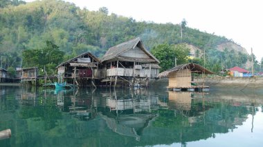 Banay Banay, Davao Oriental, Filipinler - Mart 2016: Filipinlerin güney kesimindeki bir balıkçı köyünün lagün sularına yansıyan sazlıklar üzerindeki evler.