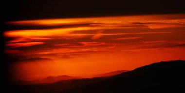 Gökyüzü alevler içinde parlak kırmızı ve portakallar üretiyor gün doğumunda gökyüzünde