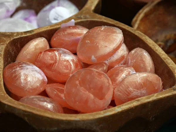 Smooth round orange gemstones in a wooden bowl