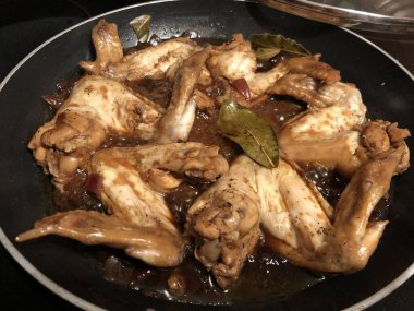 Tavuk kanatları tavada pişirilmiş, körfez yapraklı.