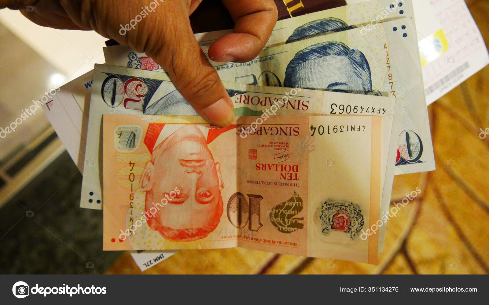 新加坡新加坡2016年3月不同数额的新加坡元票据手工持有—— 库存社论照片© GemStocks #351134276