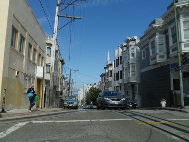 San Francisco, Kaliforniya-Temmuz 2018: Caddeyi geçmek için bekleyen iki çanta taşıyan bir kadınla sokak fotoğrafı.