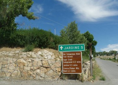 Gardiner, Montana 'daki yol kenarı tabelasında Jardine, Old Yellowstone River patikası girişi ve diğer varış noktaları yazıyor.. 