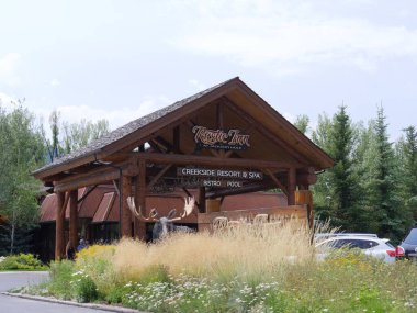 Jackson Hole, Wyoming - Ağustos 2018: Ön planda kalın çalılar ve beyaz çiçeklerle Rustic Inn 'in güzel yüzü.