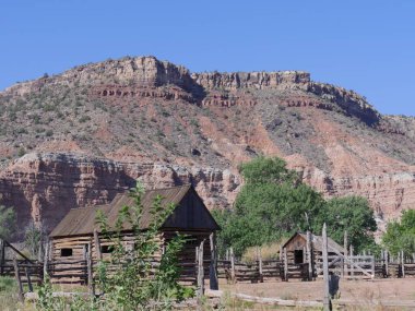 Utah 'ın Grafton hayalet kasabasındaki güzel bir kaya tepesinin eteğinde ahır evi ve arkasında güzel kırmızı kaya oluşumları olan ahşap bir kulübe..