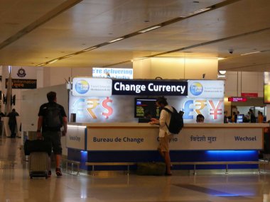 New Delhi, India- March 2018: A man stands at a currency changer outlet inside the Indira Ghandi International Airport in New Delhi. clipart