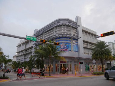 Miami, Florida- Aralık 2018: İnsanlar Collins Bulvarı 'nda arka planda mağazalarla karşıdan karşıya geçiyor..
