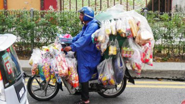 Kuala Lumpur, Malezya - Mart 2018: Bir adam Kuala Lumpur 'da aşırı abur cubur ve yiyecek içeren tek bir motosiklet kullanıyor.