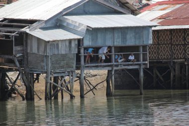 Surigao del Sur, Filipinler- Ağustos 2014: İnsanlar Liangga, Surigao del Sur 'da bir balıkçı köyünde ayaklıklar üzerindeki bir evden balık besliyor.