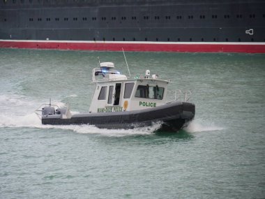 Miami, Florida- Aralık 2018: Miami-Dade polisinin lastik sürat teknesi liman kanalından bir yolcu gemisine eşlik ediyor..