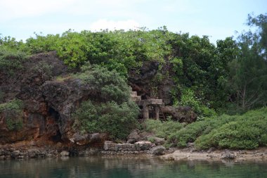 Guam 'da kayalık bir uçurum ve yeşil bitki örtüsüyle İnarajan Körfezi' nin berrak suları