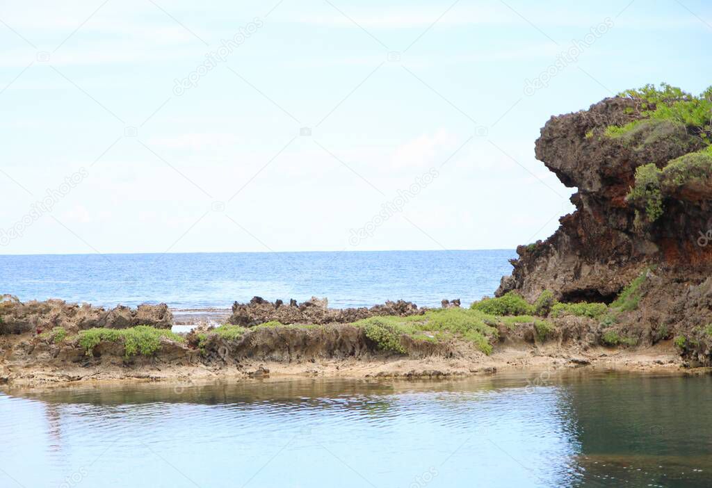 Clear waters of Inarajan Pool with the ocean in the background,  with a rocky cliff in between