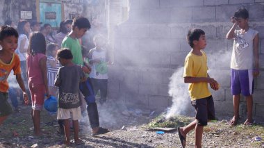 Tagum City, Filipinler- Mart 2016: Batıl inançların ardından, çocuklar ölü bir akrabalarını gömdükten sonra küçük bir şenlik ateşinin üzerinden yürüyorlar. 