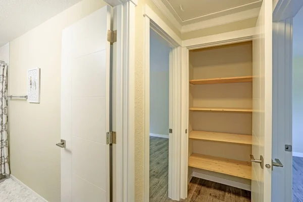 Puerta blanca se abre a una despensa de cocina llena de estantes de madera — Foto de Stock