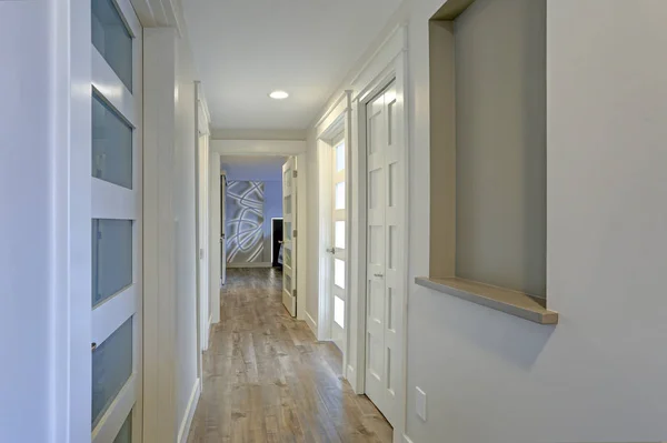 Long, narrow corridor with white doors accented with glass panels — Stock Photo, Image