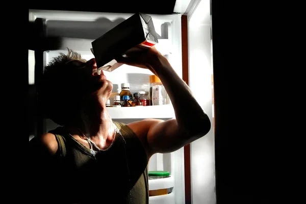 Homem bebe leite da geladeira — Fotografia de Stock