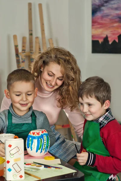 children draw at the table with the teacher