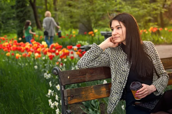 La chica se sienta en un parque en un banco —  Fotos de Stock