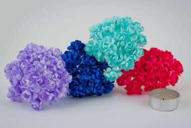 Beyaz arkaplanda çok renkli yapay çiçekler.