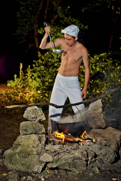 Um homem num fato de cozinha perto do fogo — Fotografia de Stock