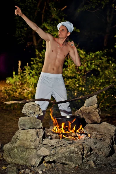 Um homem num fato de cozinha perto do fogo — Fotografia de Stock