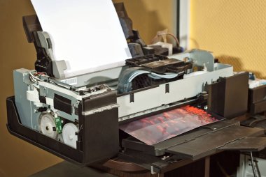 Atölyedeki eski bozuk yazıcı. Yazıcıları temizleme ve kalibre etme kavramı. Gün batımı ve kırmızı gökyüzü, fotoğrafta bulutlar var. Matbaa malzemelerinin üzerine basılmış resimli doğa fotoğrafı.