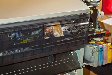 Atölyedeki eski bozuk yazıcı. Yazıcıları temizleme ve kalibre etme kavramı. Fotoğrafta günbatımı, çadır ve yeşil çimen var. Matbaa malzemelerinin üzerine basılmış resimli doğa fotoğrafı.