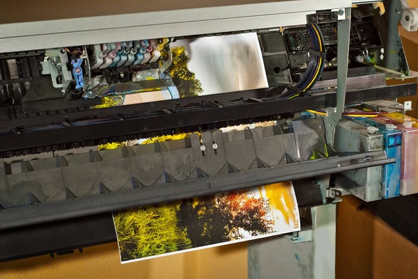 Old broken printer in workshop. The concept of cleaning and calibrating printers. Sunset, tent and green grass in the photo. Picturesque nature photo printed on printing equipment.