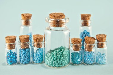 Parlak mavi arka planda cam kavanozlarda mor ve cyan boncuklar. Tahta mantarlı şeffaf bir kabın içinde boncuklar. Düzen, denge ve kaos kavramı..