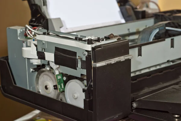 The printer is disassembled into parts. Broken, dirty and dusty printer. Service center for equipment repair. Refilling with ink and cleaning of printing equipment.