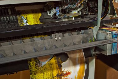 Atölyedeki eski bozuk yazıcı. Yazıcıları temizleme ve kalibre etme kavramı. Fotoğrafta günbatımı, çadır ve yeşil çimen var. Matbaa malzemelerinin üzerine basılmış resimli doğa fotoğrafı.