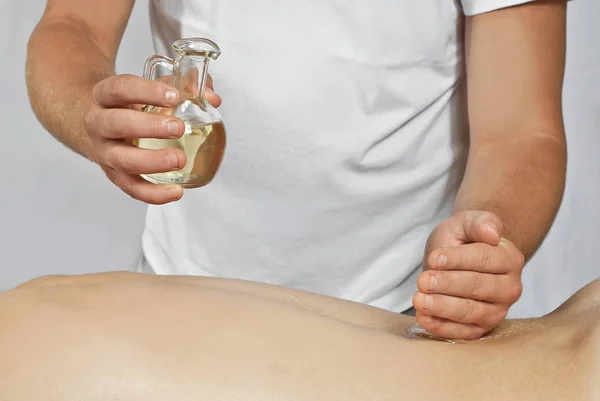 Massagetherapeut Weißen Shirt Gießt Massageöl Seine Hände Mann Reicht Nahaufnahme — Stockfoto