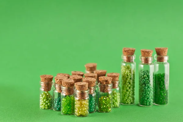 Zöld Sárga Gyöngyök Üvegedényekben Élénk Zöld Háttérrel Gyöngyök Átlátszó Tárolóedényben — Stock Fotó