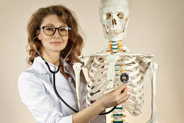 Beyaz Tıp Önlüklü Kadın Sarı Arka Planda Iskelet Yapısı Olan — Stok fotoğraf