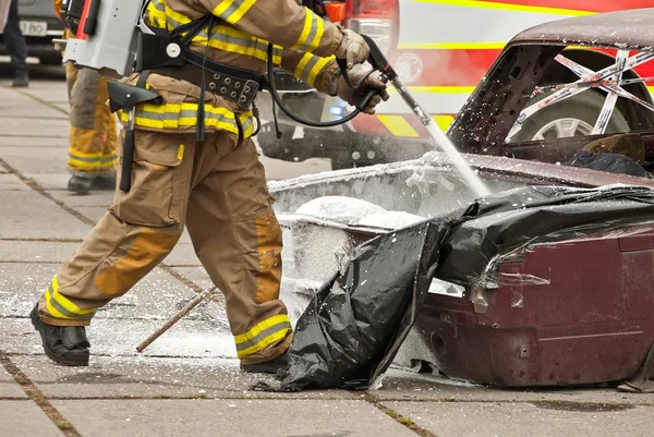 The fireman extinguishes the burned car. Training firefighters. Demonstration rescue work.