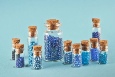 Parlak mavi arka planda cam kavanozlarda mor ve cyan boncuklar. Tahta mantarlı şeffaf bir kabın içinde boncuklar. Düzen, denge ve kaos kavramı..