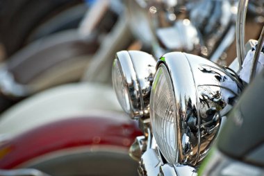 Motosikletler arka arkaya yerleştiriliyor. Farlar yakın çekim. Motosiklet krom elementleri.