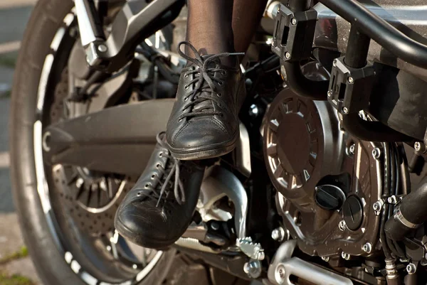 Motosiklet tekerleği yakın plan. Motosiklet metal parçaları. Şehirde motorcu buluşması. Çocuklar motosiklete biner. Küçük bacaklar yakın..