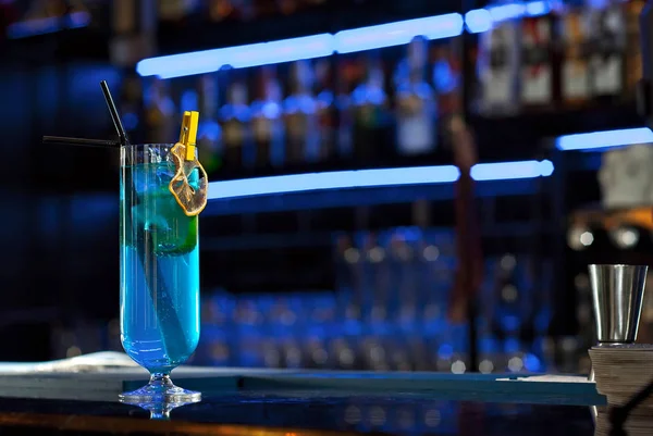 バーカウンターでブルーカクテル アルコールとボトルの背景にマティーニ ウォッカ テキーラとフルーツを飲みます 板に酒を盛ったガラス — ストック写真