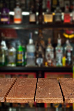 Alkollü şişelerden oluşan tahta bir arka plan. Tasarım için eski bar tezgahı. Tasarım için bir eser. Reklam yapmak için boş bir yer. Arkaplanda çubuğun içi bulanık.