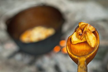 Patatesler büyük bir tencerede ateşte pişirilir. Yürüyüş koşullarında kamp ateşinde yemek pişirilir..