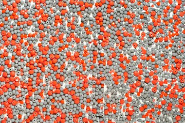 Beyaz arka planda çeşitli mücevherlerin dokusu. Gri ve turuncu taşlar. Boncuk ve kolyeler duvara yapıştırılmış..